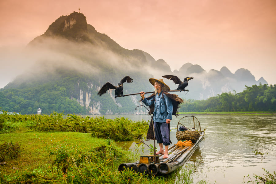 persona con sombrero viajando en lancha en el lago de yangshuo